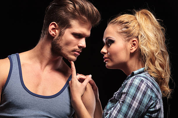 Casal em clima íntimo: a mulher segura o queixo do homem com leveza e firmeza, olhando em seus olhos com autoridade, como toda hotwife dominante deve ser.